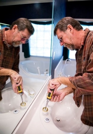 old man using screwdriver to fix sink at townsville handyman
